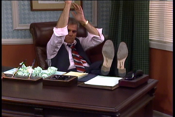 Charlie Polniaczek sits with his feet on a desk, throwing wadded-up pieces of paper like small basketballs.